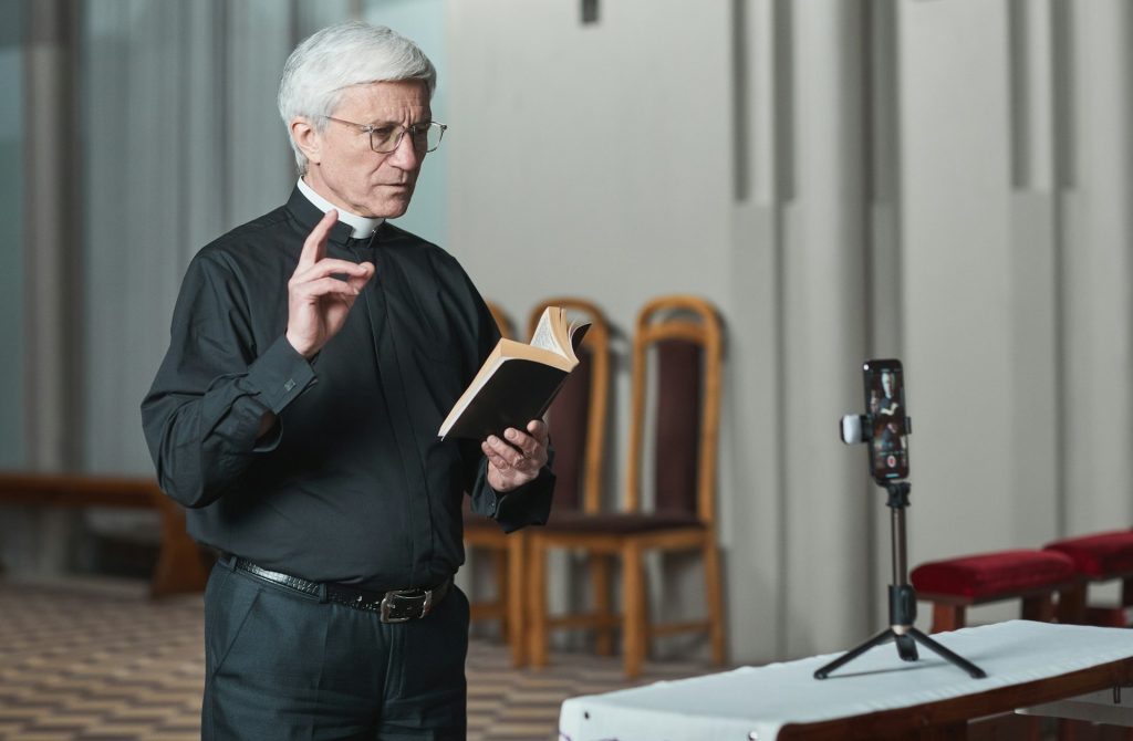 Pastor predigt vor einer Digitalkamera