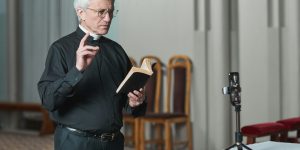 Pastor predigt vor einer Digitalkamera