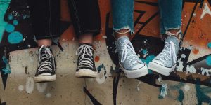 Kinderbeine mit Turnschuhen vor einer bunten Wand