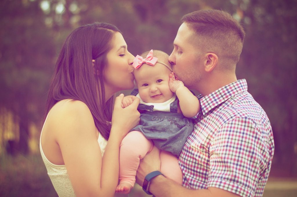 Vater und Mutter küssen ein Kleinkind